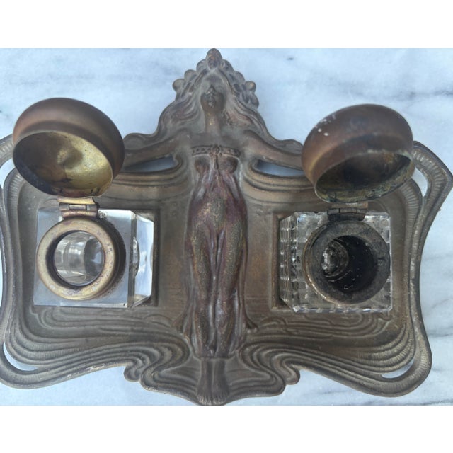French Art Nouveau double inkwell desk stand. Cast from heavy metal with a dark aged patina featuring a figural maiden...
