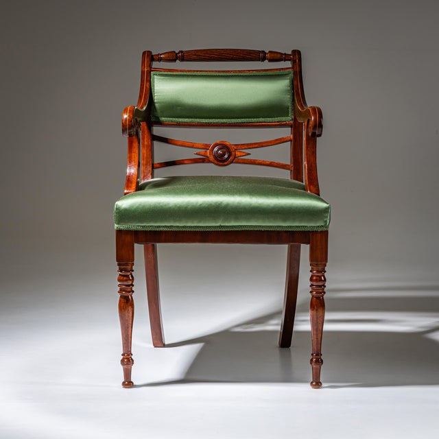 Biedermeier armchair raised on front baluster legs and slightly curved rear legs. The armrests terminate in volutes and...