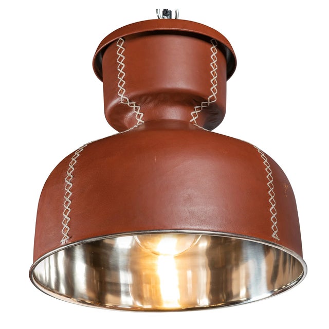 The Small Leather Dome Pendant is crafted of a top grain leather atop spun chrome with cream-colored baseball stitching...