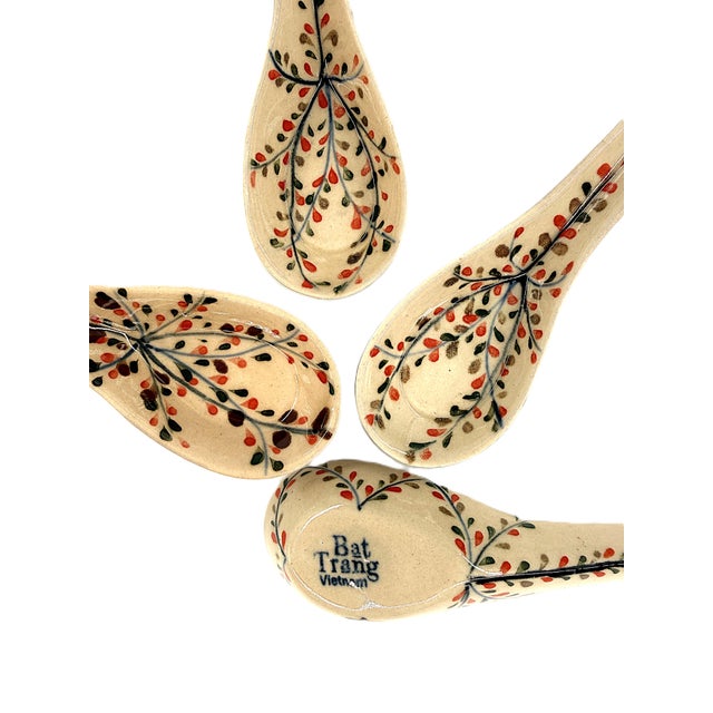 A beautiful set of six ceramic soup spoons from Bat Trang, Vietnam, featuring delicate botanical decoration in warm,...