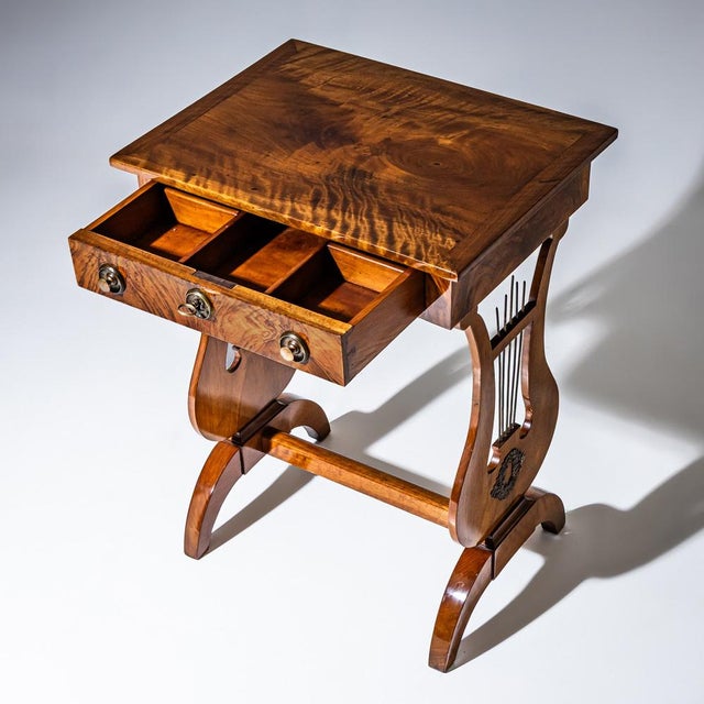 Biedermeier sewing table veneered in walnut with one drawer and brass fittings. The interior is fitted with small...