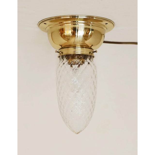 Art Nouveau/Art Deco ceiling lamp, circa 1920. Dish-shaped brass body. Clear glass shade with diamond pattern. The lamp...