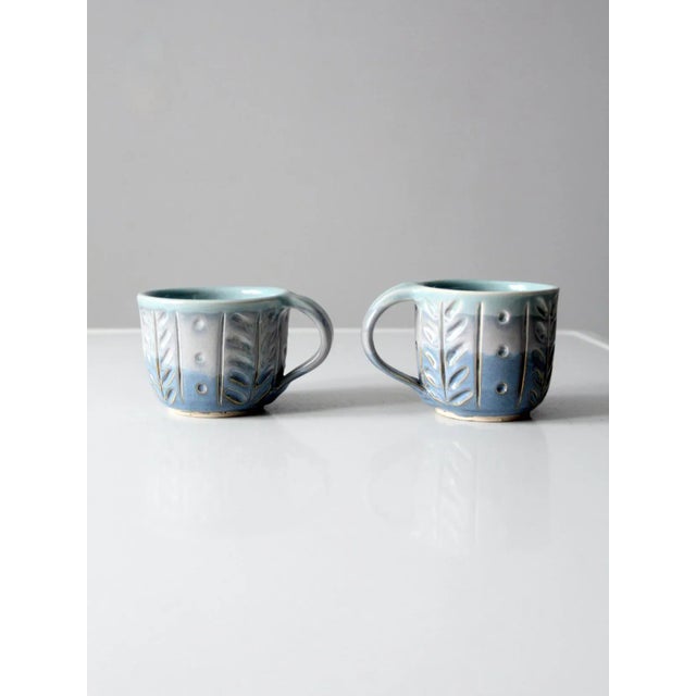 This pair of vintage studio pottery mugs is hand-crafted with a beautiful three-tone glaze in soft blues and grays. Each...