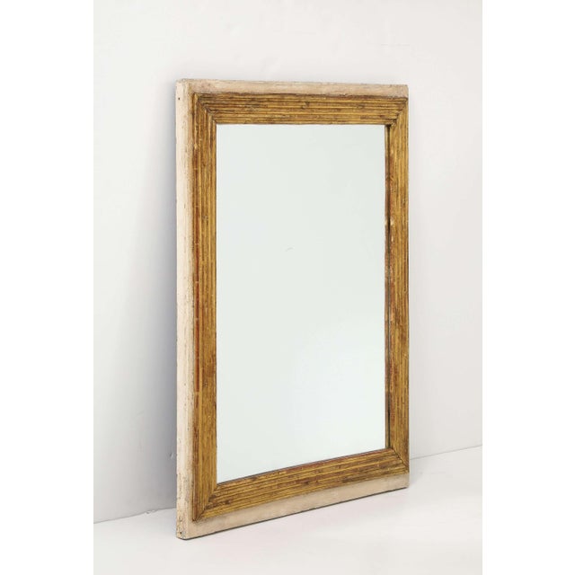 A Louis XVI style rectangular mirror featuring a giltwood, finely reeded inner frame surrounded by a softly time-worn...
