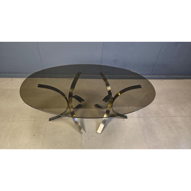Gorgeous brass dining table with a smoked glass oval top. Two brass tripod bases in the style of Osvaldi Borsani. Timeless...