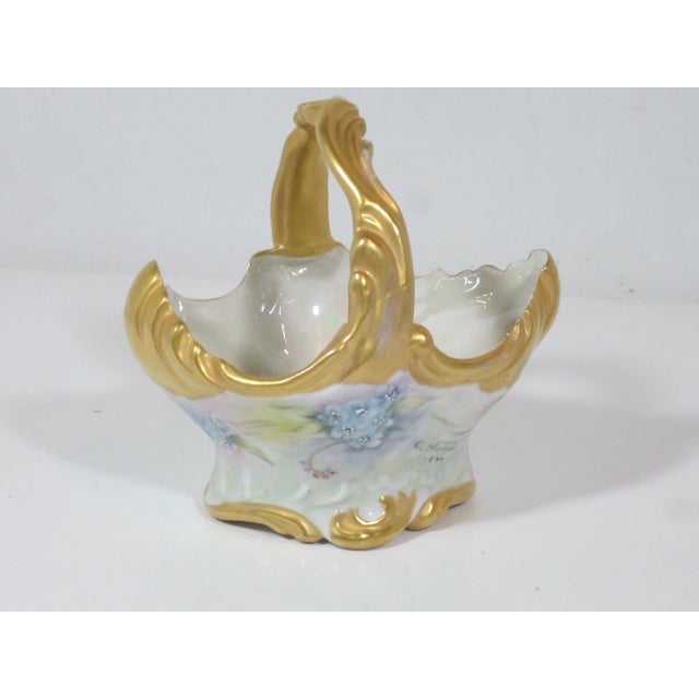 Lovely porcelain basket, hand painted with a blue floral design on a soft green background with gold accents, and luster...
