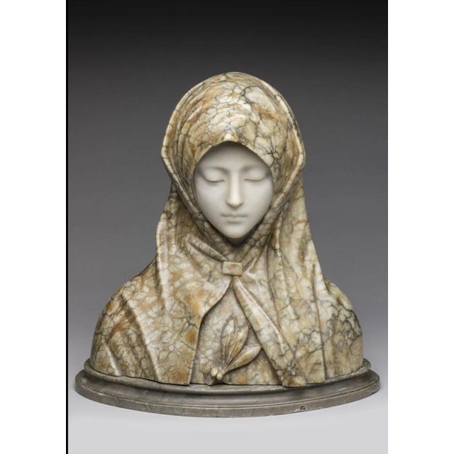 Libero GREMIGNI. Marble and alabaster sculpture depicting a bust of the Virgin Mary on an oval gray marble plinth, with a...