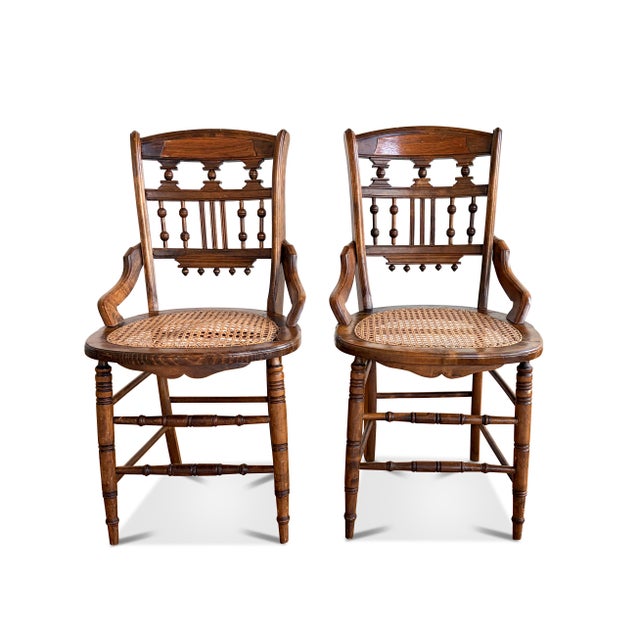 A pair of antique Victorian Eastlake style cane seat chairs. The antique cane chairs feature ornate back rests, turned...