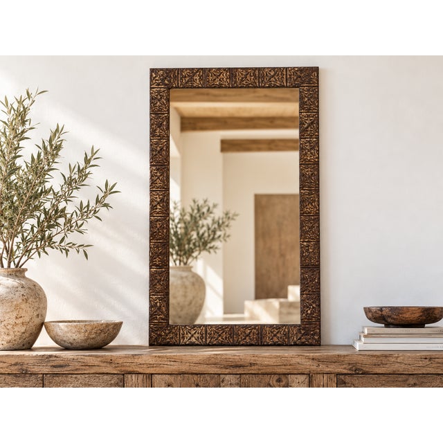 A striking example of architectural salvage repurposed as a grand mirror. The wide frame is clad in antique pressed tin...
