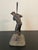 A bronze figural sculpture of a baseball player captured mid-swing, bat raised overhead in batting stance with a period...