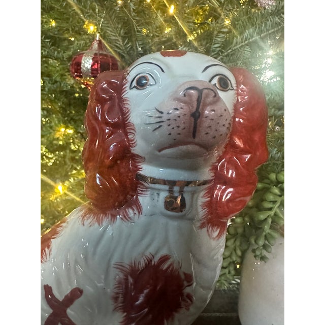 Antique English Staffordshire-style spaniel figurine modeled in a seated pose, finished in a rich iron-red and soft cream...