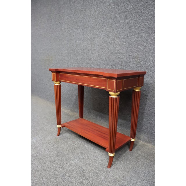 Mahogany console table by McLain Wiesand with classic inlay detail. Features fluted legs, brass-tone accents, and a lower...