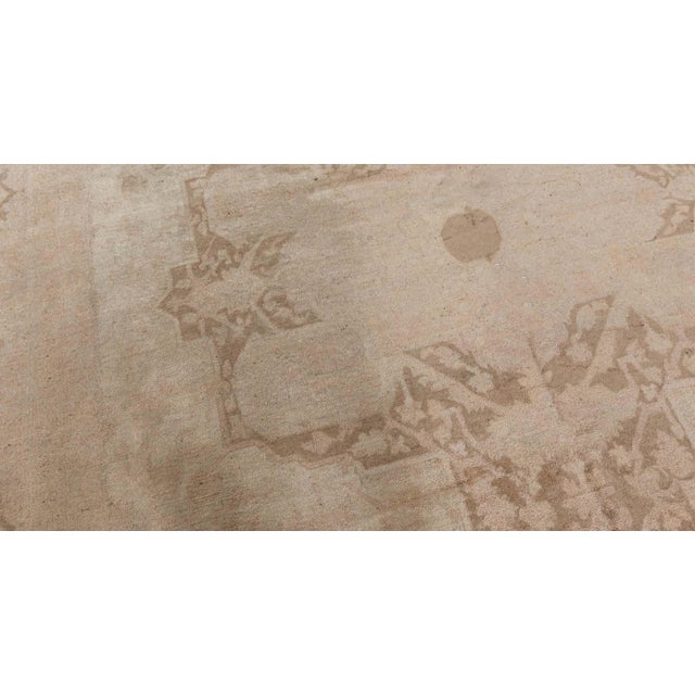 This turn of the century antique Indian Amritsar rug features a large center medallion in shades of cool brown and an all-...