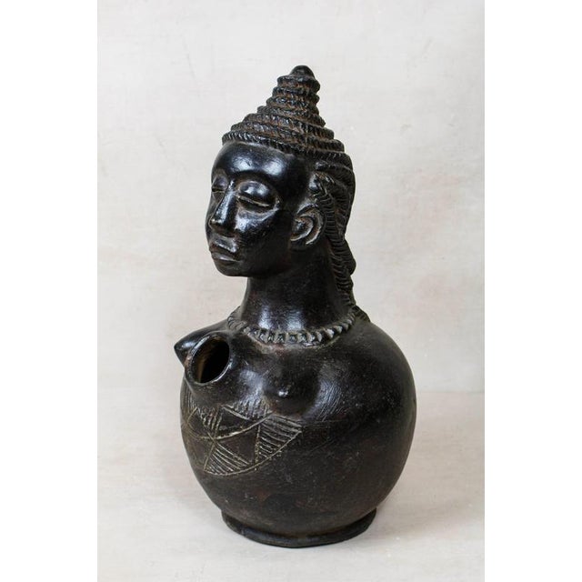 This exquisite mangbetu bust vase is a striking marriage of functional pottery and sculptural artistry, originating from...