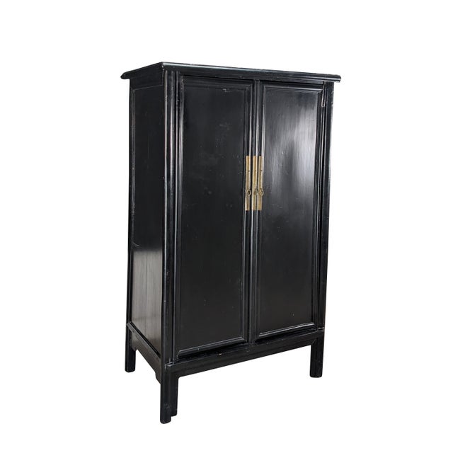 An Antique Chinese Qing Dynasty Wedding Cabinet. Features an elm frame with mortise and tenon construction and a black...