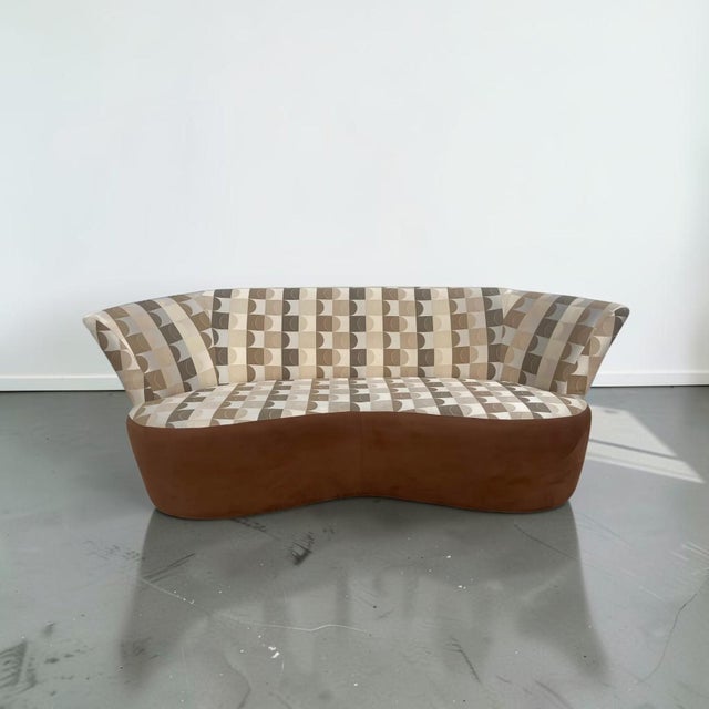 A sleek modern sofa in the style of Weiman for Preview. This piece features a curved design with a thick brown wrap-around...