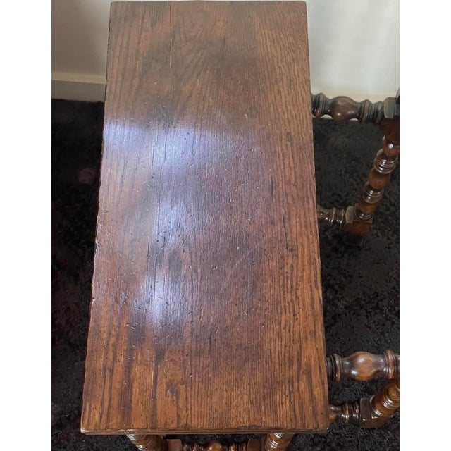 This handsome antique-style wooden side table features an elegant, narrow silhouette with richly detailed turned legs and...