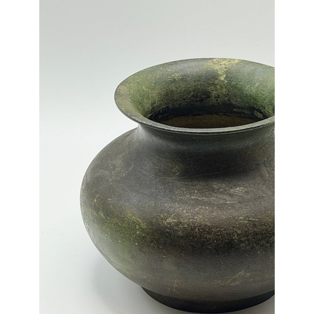 This antique bronze vase features a softly rounded, classical form with a gently flared lip and a beautifully aged...