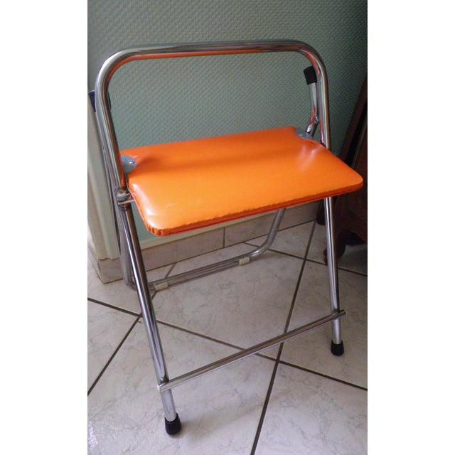 A functional piece of occasional furniture typical of the 1970s, with its bright orange faux leather seat (seat height 60...