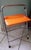 A functional piece of occasional furniture typical of the 1970s, with its bright orange faux leather seat (seat height 60...