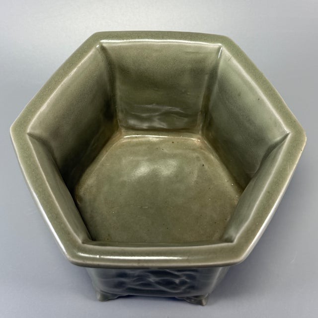 This vintage‑style handmade Longquan celadon pot adopts a six‑sided hexagonal shape with sculpted supporting feet. Each...