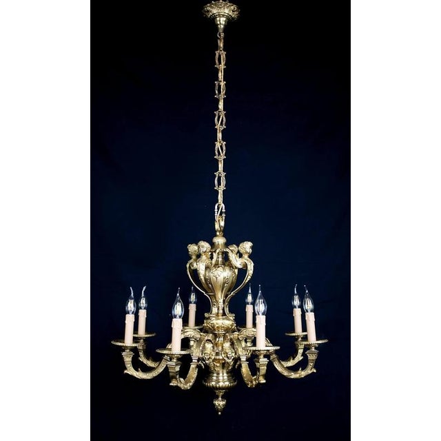 Heavy eight-armed bronze chandelier in the style of louis xiv. The upper part is decorated with cherub heads on acanthus...