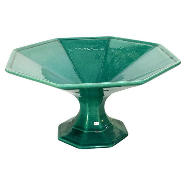 An elegant ceramic fruit bowl resting on a faceted pedestal base, inspired by Art Deco geometric lines. Its octagonal...