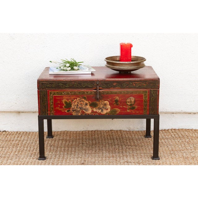 A hand-painted peony spray in cream and blush tones covers the front panel of this trunk, bordered by a scrolling black-...