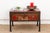 A hand-painted peony spray in cream and blush tones covers the front panel of this trunk, bordered by a scrolling black-...