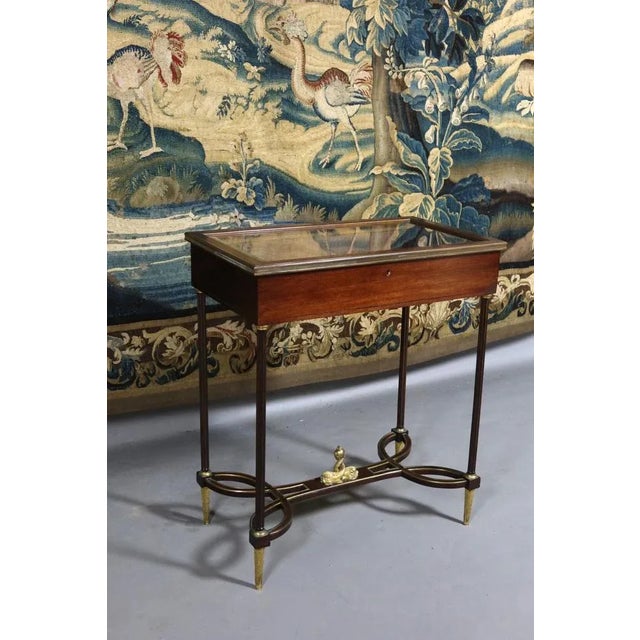 Mahogany presentation showcase resting on four feet gathered by a spacer, adorned with gilded bronze, whose part central...