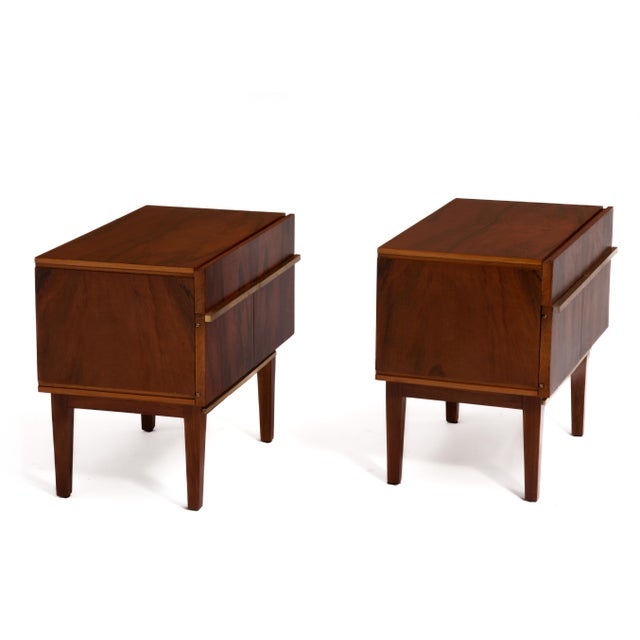 A pair of rosewood and brass nightstands after the designs of William Hinn. Wonderful book matched grain across both...