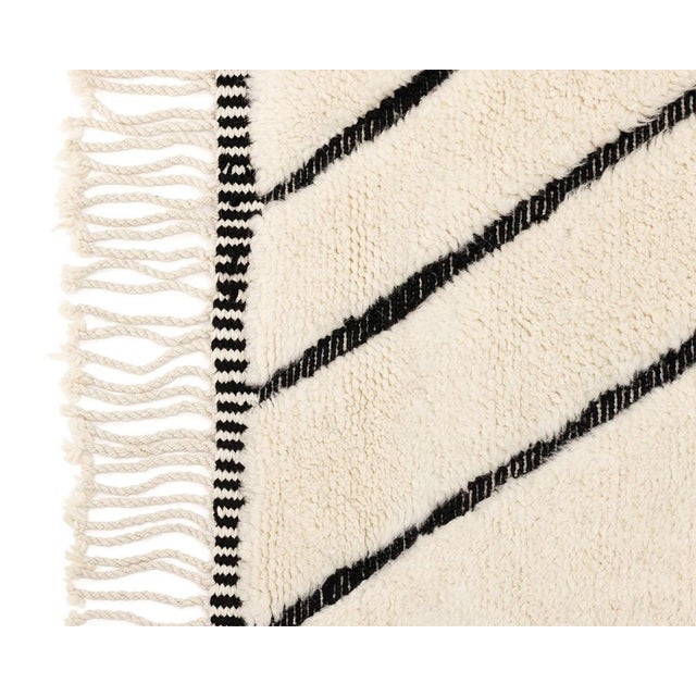Sophisticated hand-knotted wool rug in Ivory, accented with a flat-woven geometric pattern of intersecting Midnight Black...