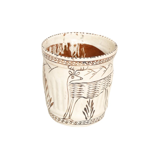 A primitive style terracotta planter. Hand painted with stylized deer, mountains and bushes, with simple brush strokes in...