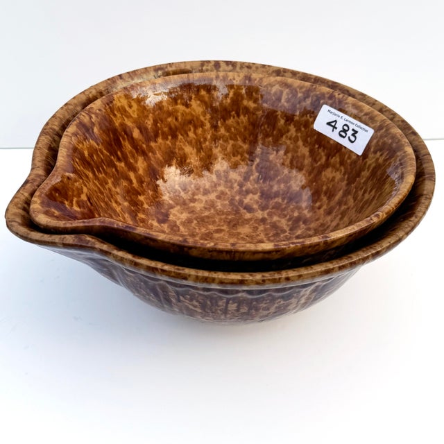 This rare pair of antique spongeware nesting mixing bowls showcases the classic Rockingham pattern with rich brown sponged...