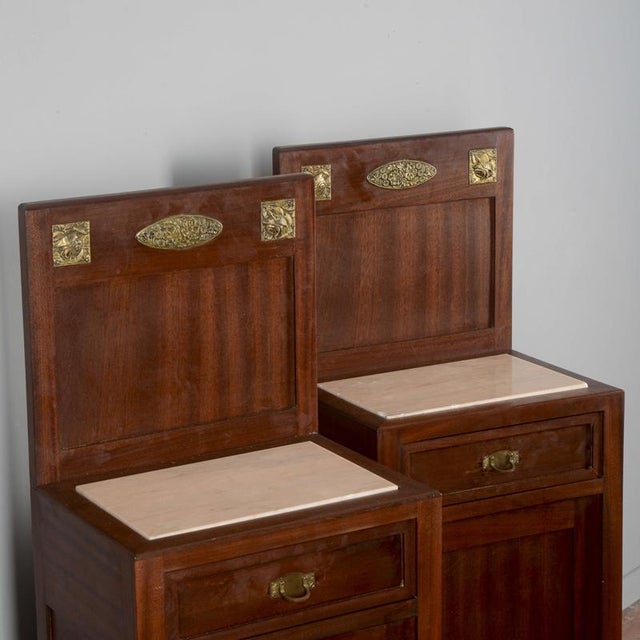 Pair of bedside tables with art nouveau marble top and mahogany veneer with decorative plaques in worked and brass-plated...