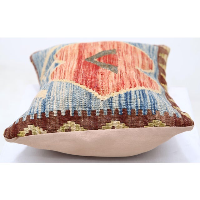 A one-of-a-kind handwoven Afghan wool kilim lumbar pillow featuring hooked center medallion in red and orange on a blue...