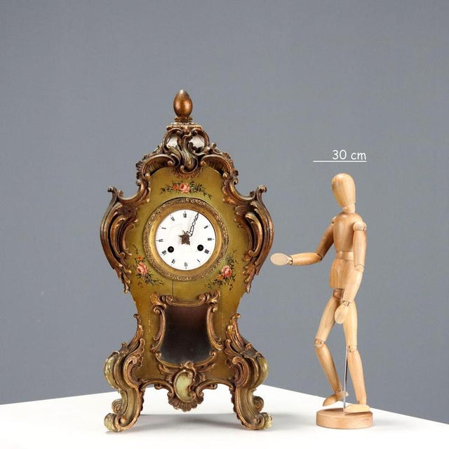 Green and gold wooden pendulum clock, carved with scrolls and painted with a polychrome flower bouquet decoration....