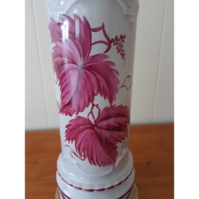 Beautiful vintage hand‑painted ceramic lamp featuring deep pink floral artwork, ribbed detailing, and warm brass accents....