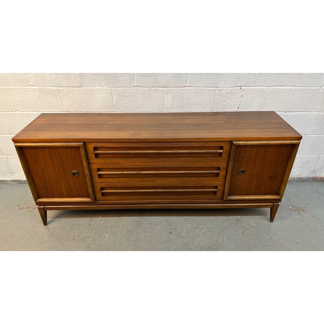 Add timeless Mid-Century Modern style and functionality to your home with this vintage walnut credenza by Bassett....