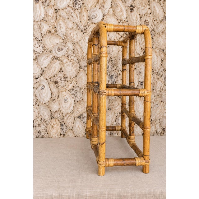 A charming vintage bamboo wine rack featuring a warm honey-toned finish, rounded architectural lines, and beautifully...
