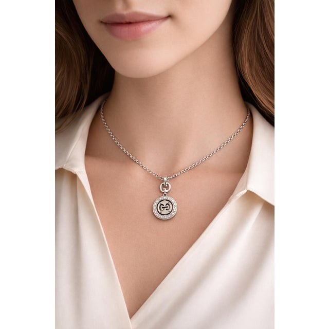 18K white gold pendant necklace by Gucci featuring a circular design with interlocking GG logo and white diamond accents....