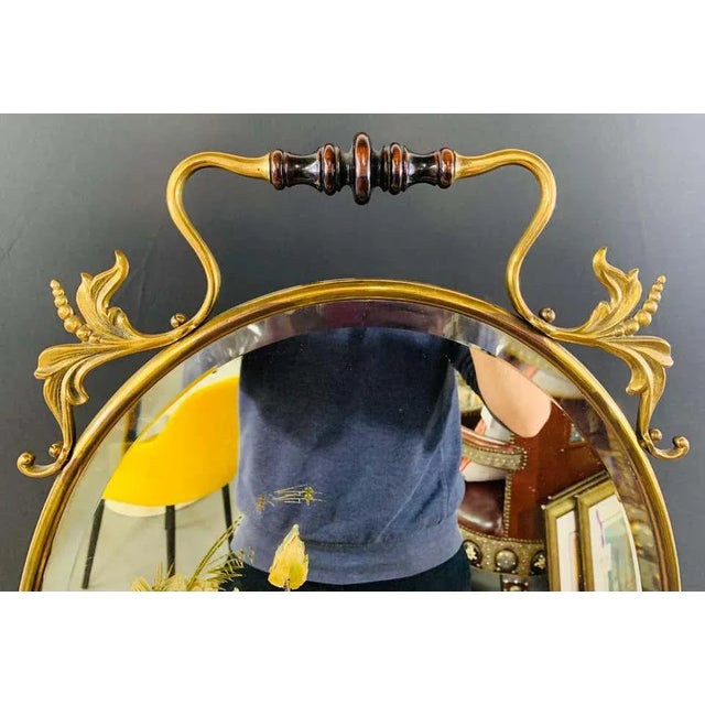 A lovely oval brass Art Nouveau mirror. The mirror features a wooden handle and fine brass frame in a very elegant floral...