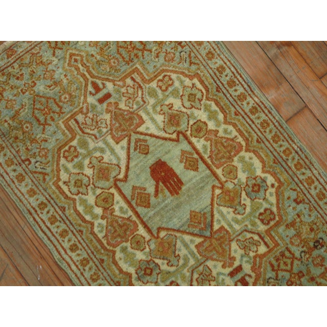 An early 20th century antique Persian Senneh Mat featuring a small hand inside a blue green medallion. Accents in blue,...