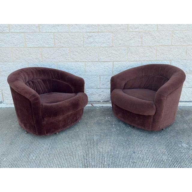 Pair of vintage barrel lounge chairs featuring rounded silhouettes, curved wraparound backs, channel-tufted detailing, and...