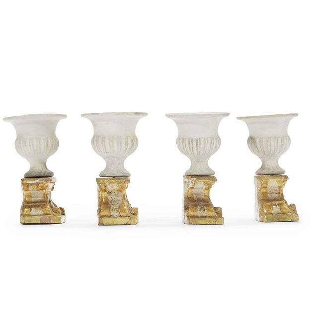 Four Neoclassical table decorations composed of four carved, lacquered, and gilded wooden bases and a Medici biscuit vase...