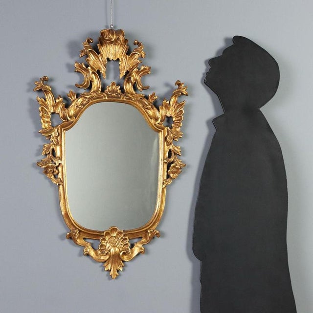 Carved and gilded wood mirror from late 19th century Italy. The design features a shaped central mirror framed by an...