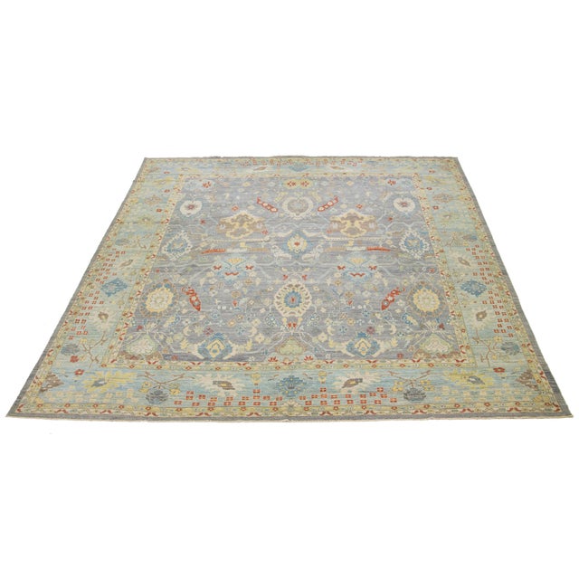 This oversized hand-knotted wool rug has a gray background adorned with multicolor accents all-over designs. This rug...