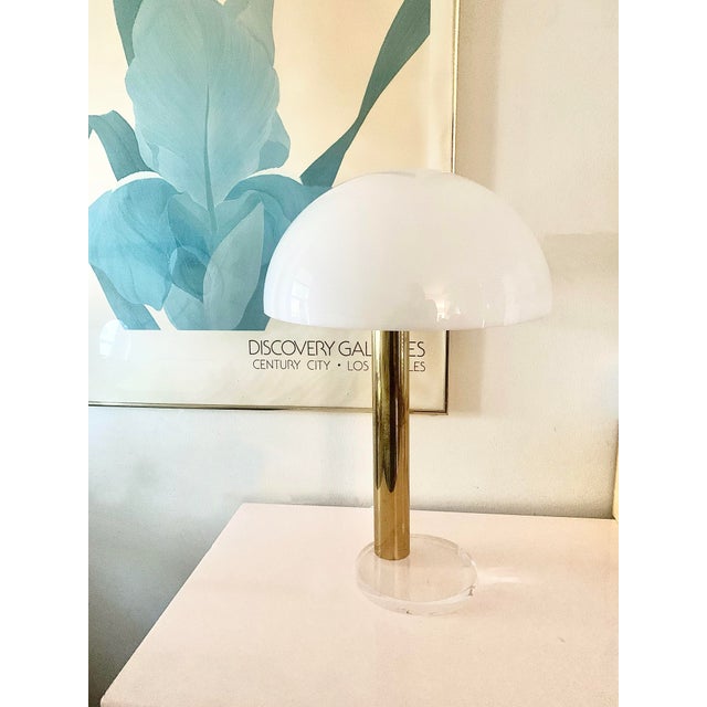 A Gage Cauchois brass and Lucite table lamp. The three-way dimmer is touch-controlled on the brass stem. Lucite base and...