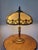 Antique Rainau cast metal table lamp featuring an ornate Tudor Revival design with an eight-panel caramel slag glass...