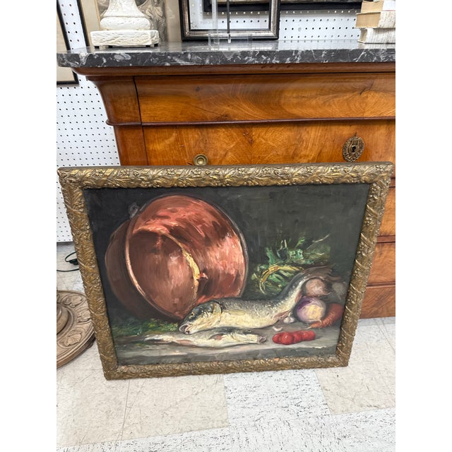This is an oil still life in the classic kitchen-table tradition. A large copper cauldron lies tipped on its side at the...